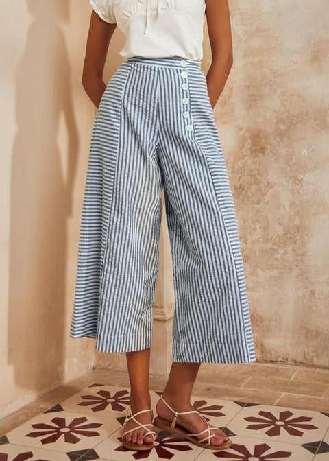 Person wearing blue and white striped pants against a beige wall.