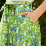 Close-up of The Garden Stroll Skirt in Hide & Squeak featuring illustrated mice, butterflies, wildflowers, side seam pockets, and a removable self-tie sash.