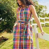 Woman wearing a vintage-inspired sleeveless plaid cotton shirt dress with pockets and a tie waist.