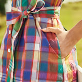 Close-up of the vibrant woven plaid fabric, side seam pocket, and self-tie waist belt on a vintage style dress.