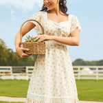Woman in a floral dress holding a basket outdoors with a clear blue sky.