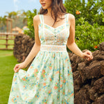 Woman in a mint green sleeveless floral dress standing outdoors with greenery in the background