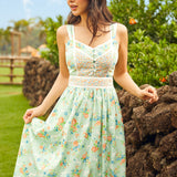 Woman in a mint green sleeveless floral dress standing outdoors with greenery in the background