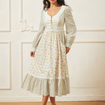Woman wearing a white floral dress against a white wall.