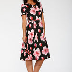 Woman wearing a black dress with pink floral pattern on a white background