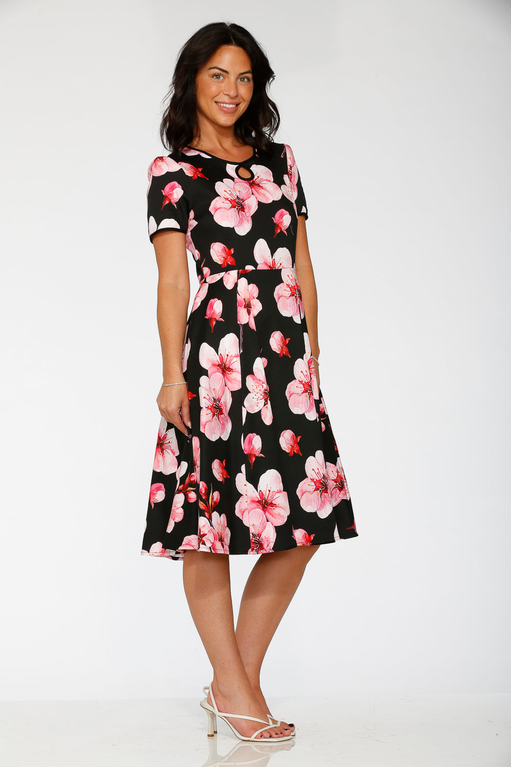 Woman wearing a black dress with pink floral pattern on a white background