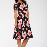 Woman wearing a black dress with pink floral pattern on a white background