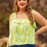 A woman wearing a light green, lemon-patterned blouse with ruffled spaghetti straps and a button-down front, paired with blue jeans.