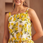 Woman wearing a summer top with lemon pattern against a neutral background