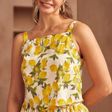 Woman wearing a summer top with lemon pattern against a neutral background