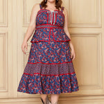 A woman models the GUNNE SAX for ModCloth Grace Peplum Midi Dress, featuring a floral pattern with red accents, a peplum bodice, and a fully lined, tiered skirt.