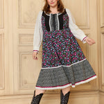 A woman modeling a GUNNE SAX for ModCloth Madilyn Midi Dress with floral prints, featuring a corset-inspired bodice, long sleeves, and black boots.