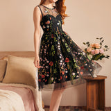 Woman wearing a sleeveless fit-and-flare party dress with sheer embroidered floral mesh and full skirt.