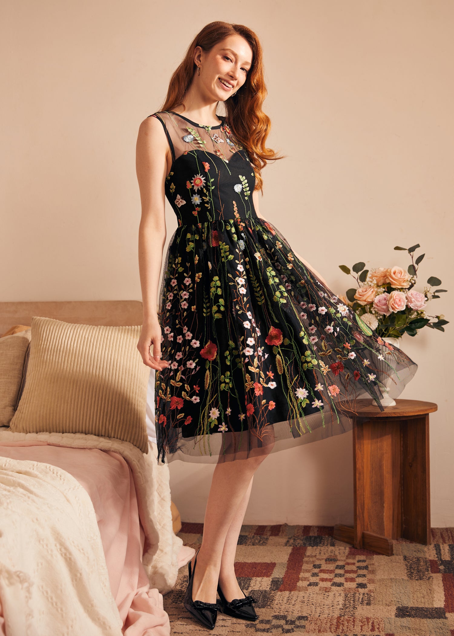 Woman wearing a sleeveless fit-and-flare party dress with sheer embroidered floral mesh and full skirt.