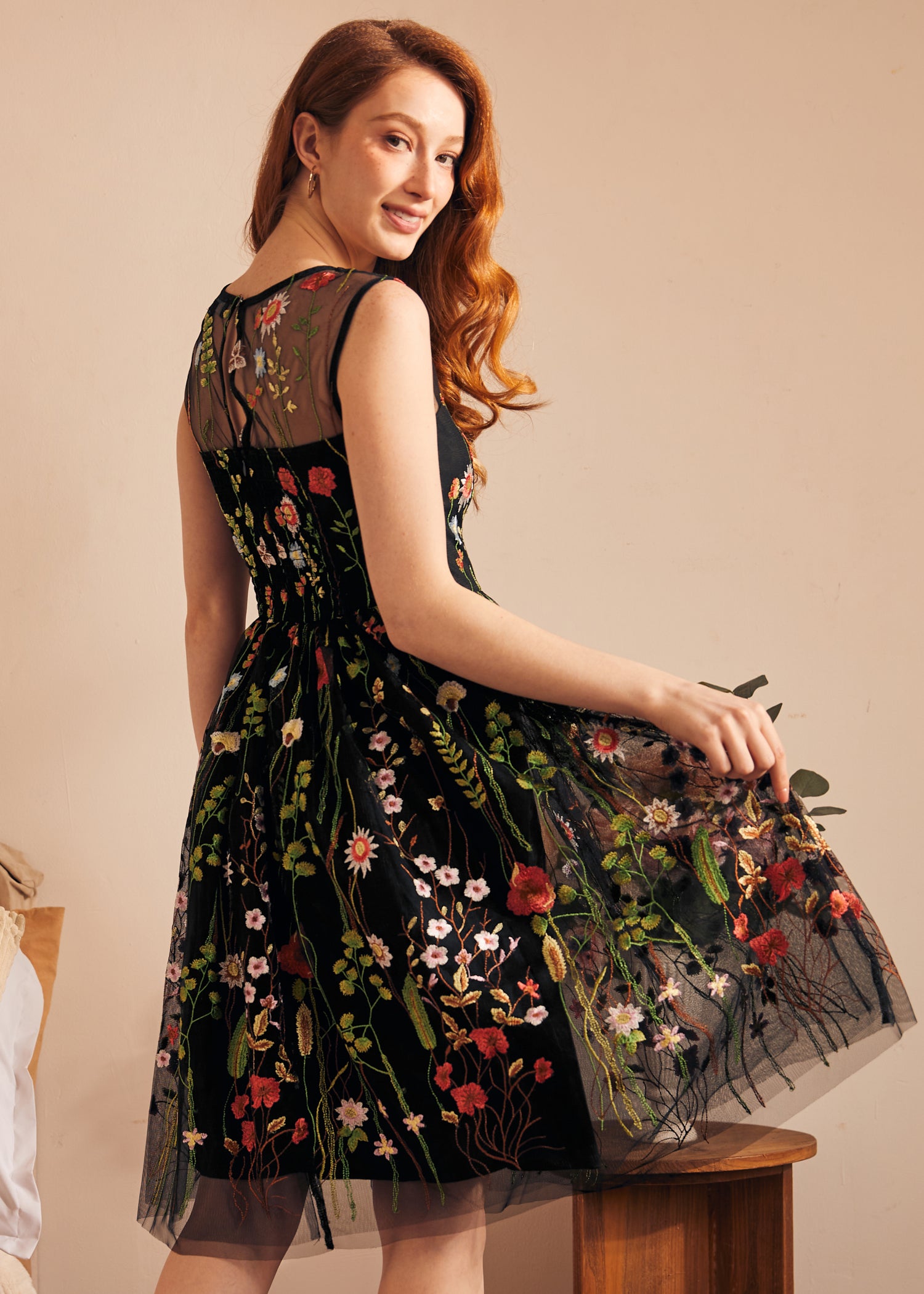 Back view of a black embroidered floral dress featuring an illusion mesh back and fit-and-flare silhouette.