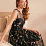Woman seated wearing a vintage-inspired black embroidered mesh dress with floral tulle overlay.