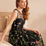 Woman seated wearing a vintage-inspired black embroidered mesh dress with floral tulle overlay.