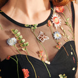 Close-up of the illusion mesh yoke with colorful floral embroidery and embroidered butterfly details on a black party dress.