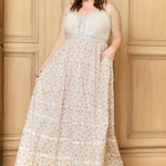 A woman modeling a sleeveless, tiered, floral maxi dress with a corset-style bodice.