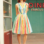 Woman wearing ModCloth Rainbow Carousel sleeveless fit-and-flare dress with rainbow stripes and polka dots.
