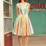 Woman wearing ModCloth Rainbow Carousel sleeveless fit-and-flare dress with rainbow stripes and polka dots.