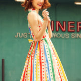 Side view of woman wearing the Rainbow Carousel sleeveless cotton dress with removable self-tie sash.