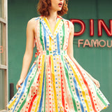 Woman wearing sleeveless rainbow striped polka dot shirt dress with button-front bodice and fit-and-flare skirt.