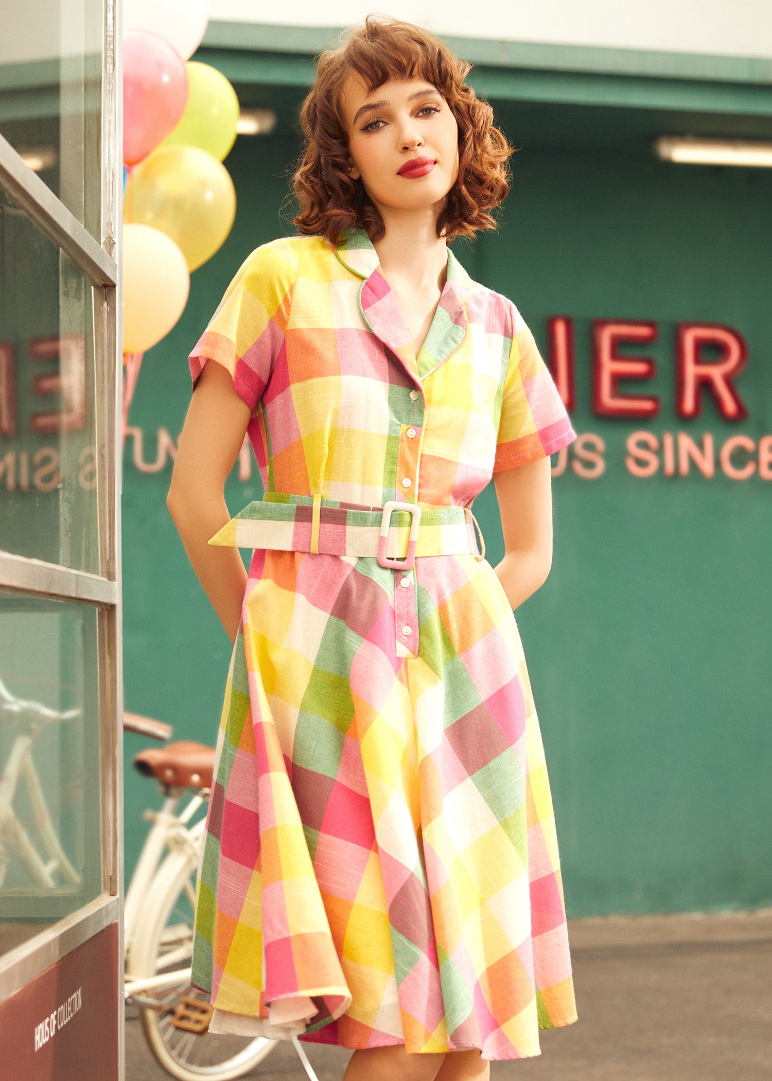 Woman wearing a retro pastel plaid shirt dress with short sleeves and a flattering full skirt.