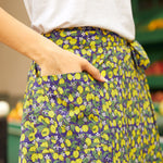 Person wearing a colorful skirt with lemon and purple flower pattern.