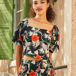 Woman wearing a floral shirt standing in front of a building entrance.