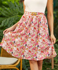 Woman wearing a pink crinkle rayon skirt with a white top in a garden setting