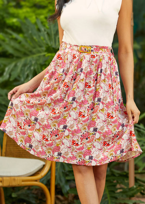 Woman wearing a pink crinkle rayon skirt with a white top in a garden setting