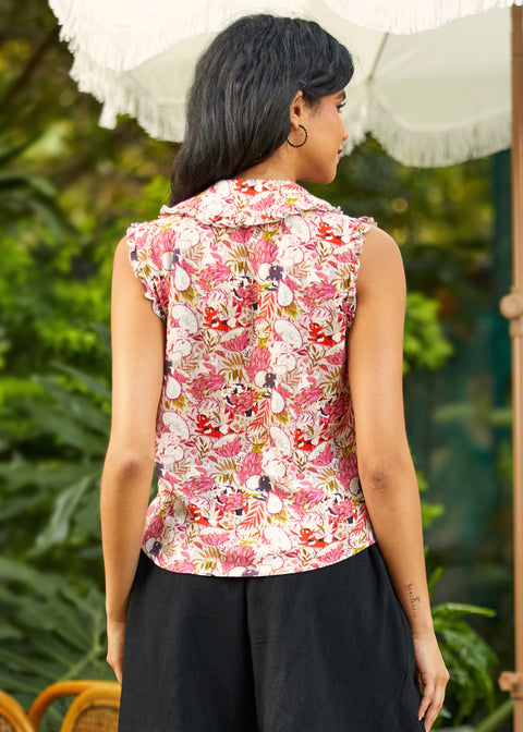 Back view of woman wearing a sleeveless floral top with a blurred green background