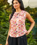 Woman wearing a floral sleeveless top with a blurred green background
