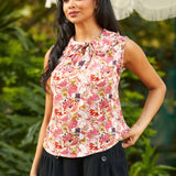 Woman wearing a floral sleeveless top with a blurred green background