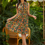 Woman in a floral dress standing outdoors with greenery in the background