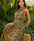 Model wearing peach print bow neck fit and flare dress with sleeveless silhouette