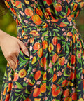 Detail of waistband and gathered skirt with side pockets on dress with vibrant fruit print