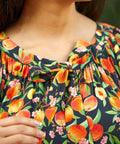 Close-up of tie neckline with gathered detail on peach print blouse
