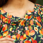 Close-up of tie neckline with gathered detail on peach print blouse