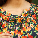 Close-up of tie neckline with gathered detail on peach print blouse