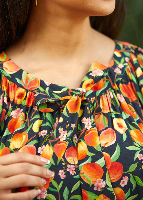 Close-up of tie neckline with gathered detail on peach print blouse