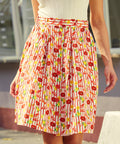 Model wearing button front skirt with red buttons and flared shape