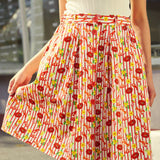 Person wearing a red patterned skirt with belt loops and elastic side detail