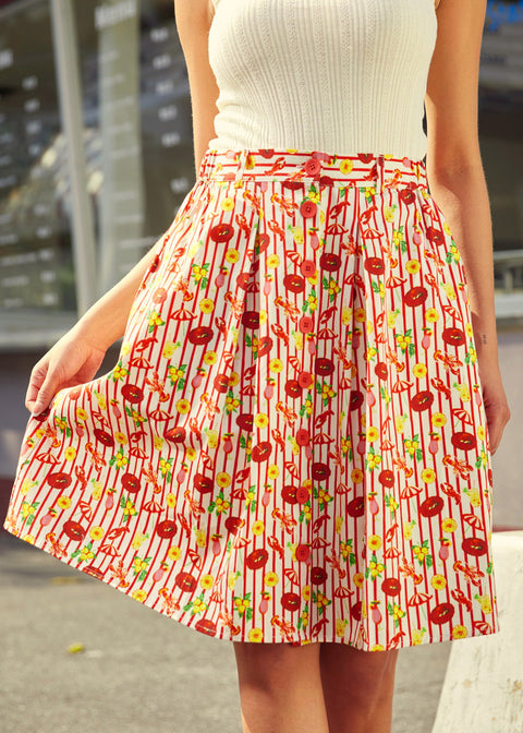 Person wearing a red patterned skirt with belt loops and elastic side detail