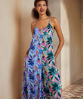 Woman wearing a colorful floral dress standing against a neutral wall.