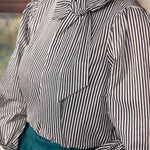 Person wearing a black and white striped blouse with a bow detail.