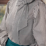 Person wearing a black and white striped blouse with a bow detail.