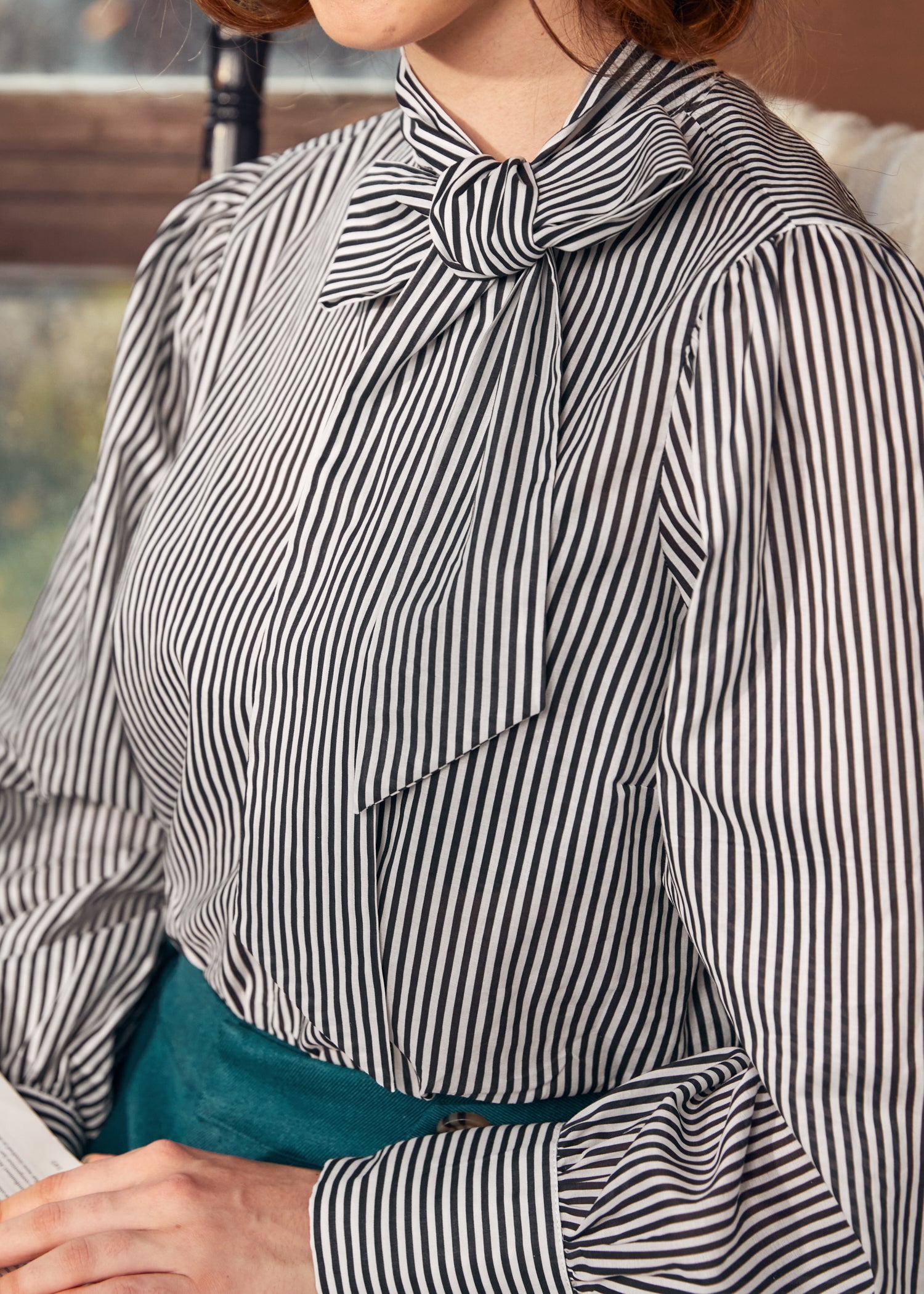 Person wearing a black and white striped blouse with a bow detail.