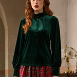 Woman wearing a green velvet blouse and red plaid skirt in an elegant interior setting.